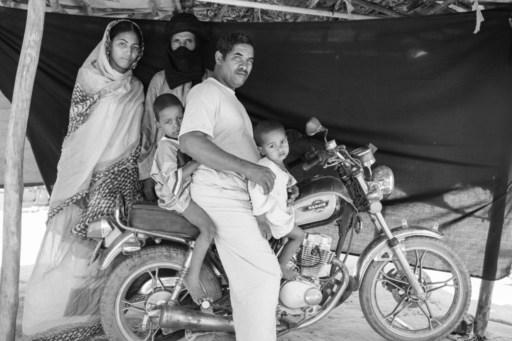 Abdou Ag Moussa, 34 años, está sentado junto a su familia sobre la moto que asegura que le salvó la vida. Brian Sokol / ACNUR