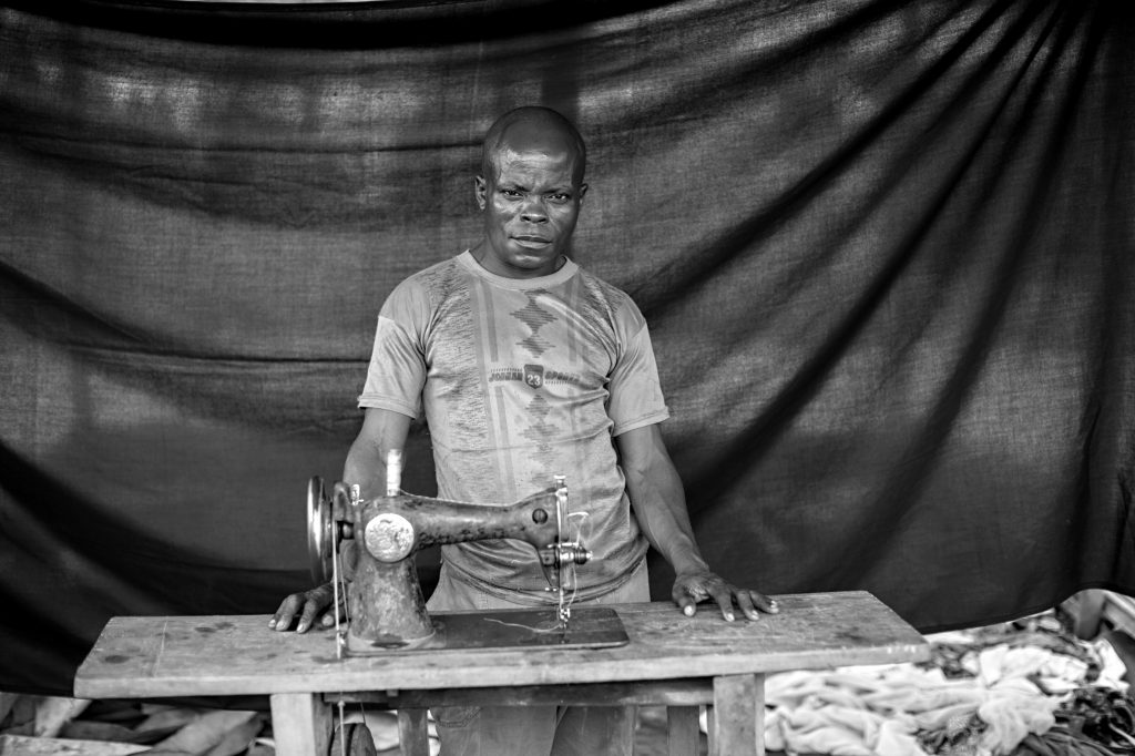 Benjamin, con su máquina de coser, de la que dice: «Es mi vida, es mi sangre. La utilizo para poder comprar comida para mi familia». Brian Sokol / ACNUR.